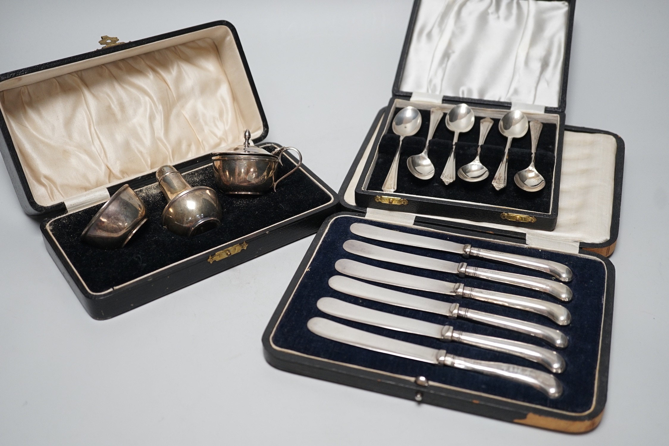 A cased George V three piece silver condiment set, Birmingham, 1928 and two other cased sets of flatware.